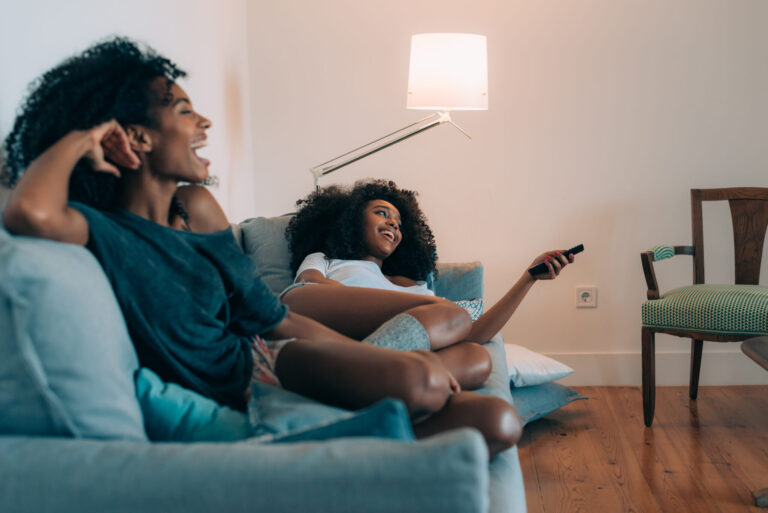 LiFi Media Production tv commercial production, Happy young two black women lying down in the couch watching tv