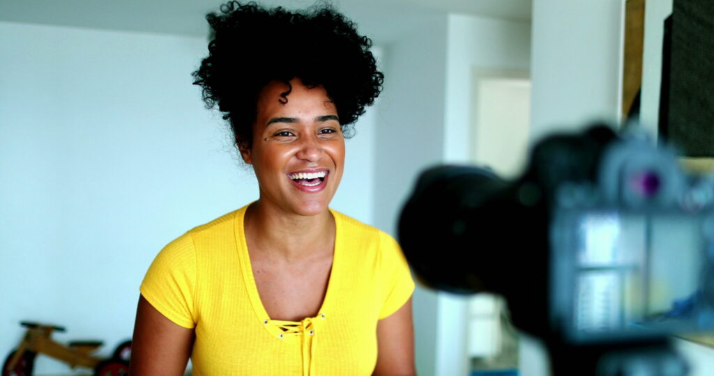 LiFi Media Production Testimonial Video Production, One young black woman speaking in front of camera giving testimony for online channel. 20s female vlogger creating video post engaged with new media