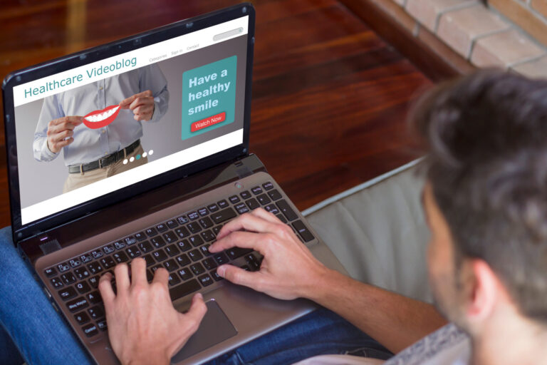 LiFi Media Production healthcare video production, Top view of young man at home visiting healthcare videoblog on his laptop. All screen graphics are made up.