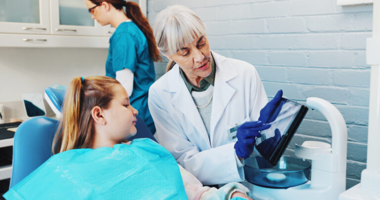 LiFi Media Production healthcare video production, Child, explain and dentist with teeth on tablet for screen, extraction information and diagnosis. Dentistry, girl kid and mature woman in practice for dental implant and tooth alignment procedure.