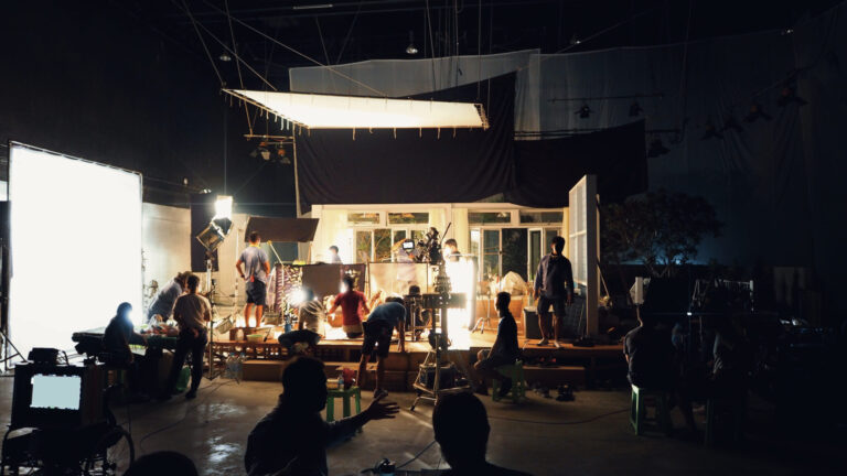 LiFi Media Production Average Cost of TV Commercial Production, Silhouette of people working in big production studio for shooting or recording movie video by digital camera and lighting set.