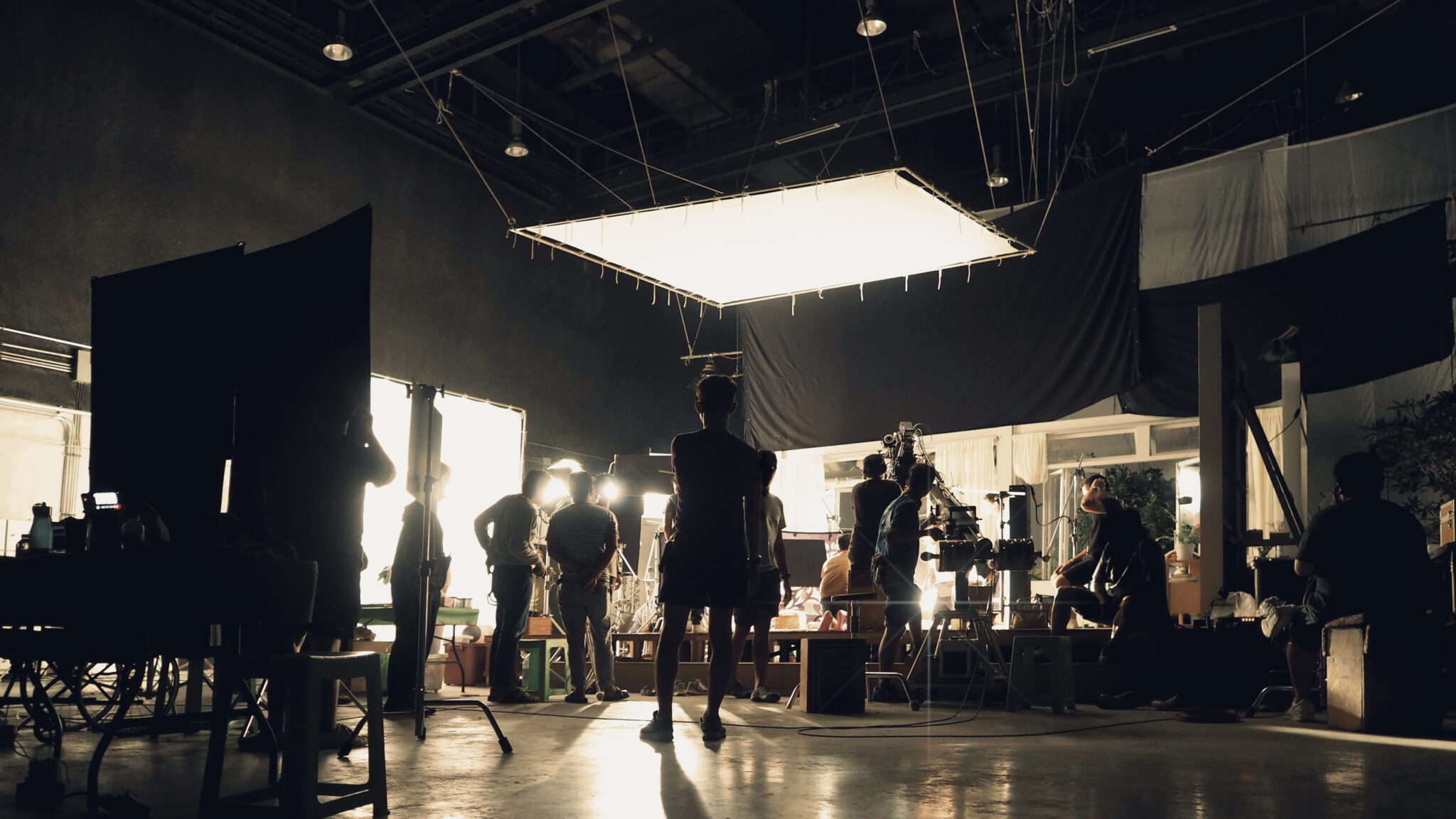 Silhouette of people working in a large production studio for shooting a video commercial with digital cameras and lighting.